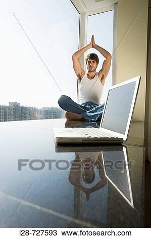Stock Image - Man sitting in yoga position on floor. Fotosearch