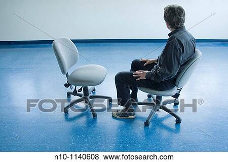 Man sitting on a chair in an empty office View Large Photo Image Stock Photo - Man sitting on a chair in an empty office. Fotosearch