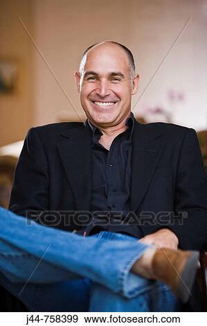 Man sitting on a chair in the house, smiling, portrait View Large Photo Image Stock Photo - Man sitting on a chair in the house, smiling, portrait. Fotosearch