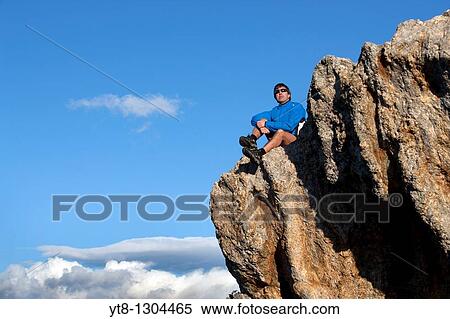 Man sitting on a rock ledge View Large Photo Image Stock Photography - Man sitting on a rock ledge. Fotosearch
