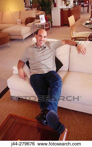 Man sitting on a sofa in a furniture store View Large Photo Image Stock Photograph - Man sitting on a sofa in a furniture store. Fotosearch