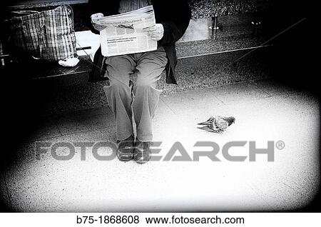 Stock Photo - man sitting on a street bench reading the newspaper. Fotosearch