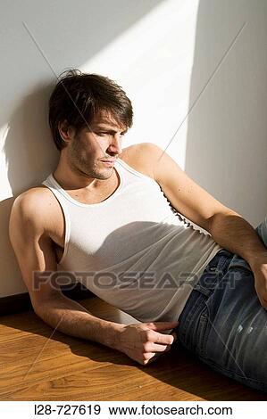 Stock Photo - Man sitting on floor, portrait. Fotosearch
