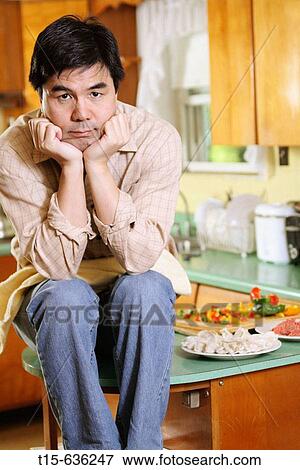 Man sitting on kitchen counter depressed with dinner ready View Large Photo Image Stock Photo - Man sitting on kitchen counter depressed with dinner ready. Fotosearch
