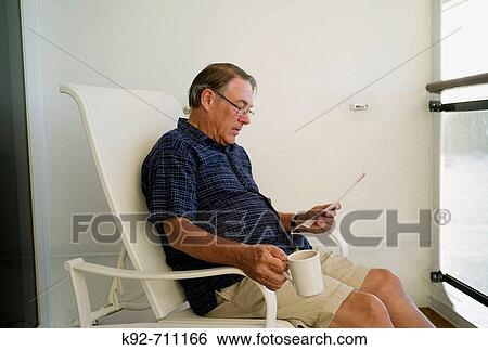 Stock Photograph - Man sitting on the balcony of a cruise ship cabin.. Fotosearch
