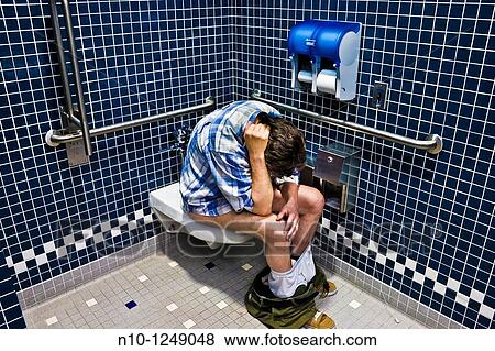 Man sitting on the toilet in an office building bathroom View Large Photo Image Stock Photo - Man sitting on the toilet in an office building bathroom. Fotosearch