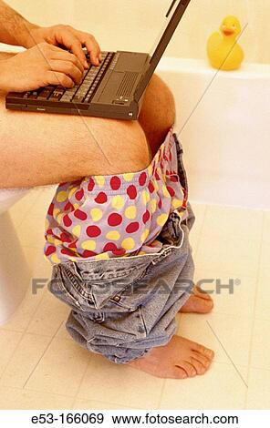Man sitting on toilet using computer View Large Photo Image Stock Photo - Man sitting on toilet using computer. Fotosearch