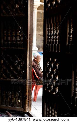 Stock Image - man sitting outside mosque, islamic cairo, cairo, egypt. Fotosearch