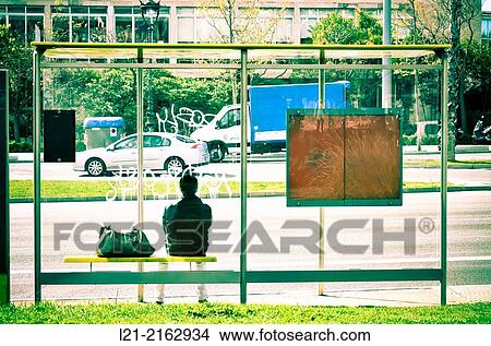 Man sitting with his bag waiting at a bus stop. Barcelona, Catalonia, Spain. View Large Photo Image Picture - Man sitting with his bag waiting at a bus stop. Barcelona, Catalonia, Spain.. Fotosearch