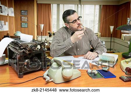 Man smoking a cigarette while work in the office, 1960's scene. View Large Photo Image Stock Photo - Man smoking a cigarette while work in the office, 1960's scene.. Fotosearch