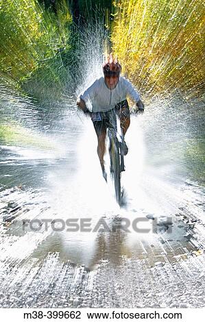 Stock Image - Man splashing through water on a mt. biking in Sun Valley, Idaho. USA. Fotosearch