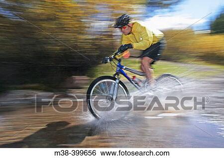 Stock Photograph - Man splashing through water on a mt. biking in Sun Valley, Idaho. USA. Fotosearch