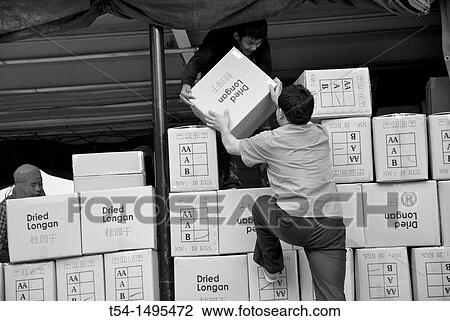 Stock Image - Man stacking boxes in a Chinese boat on the Mekong. Fotosearch