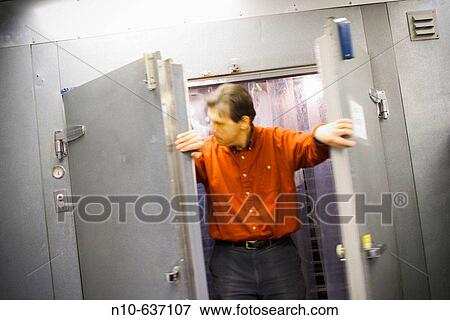 Man standing between the open doors of an industrial freezer. View Large Photo Image Stock Photo - Man standing between the open doors of an industrial freezer.. Fotosearch