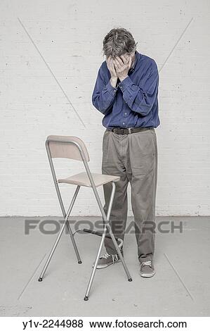 Man standing by a chair. View Large Photo Image Stock Photo - Man standing by a chair.. Fotosearch