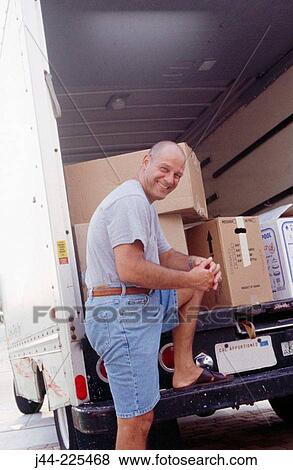 Man standing by a moving truck View Large Photo Image Stock Photo - Man standing by a moving truck. Fotosearch