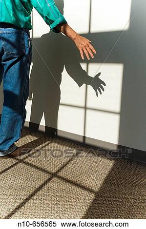 Man standing by a wall and in the shadow coming from a nearby window. View Large Photo Image Stock Photography - Man standing by a wall and in the shadow coming from a nearby window.. Fotosearch