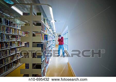 Man standing by bookshelves in a library. View Large Photo Image Stock Image - Man standing by bookshelves in a library.. Fotosearch