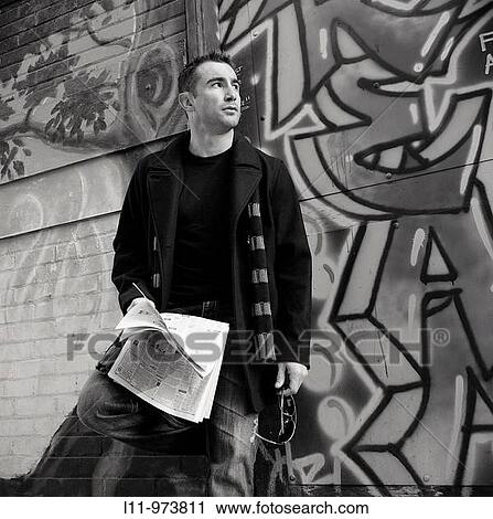 Man standing in alley with newspaper, looking off. View Large Photo Image Stock Image - Man standing in alley with newspaper, looking off.. Fotosearch