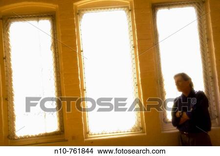 Man standing in front of brightly lit windows View Large Photo Image Picture - Man standing in front of brightly lit windows. Fotosearch