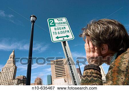 Man standing next to a sign reading? Two Hour Parking? near a city street View Large Photo Image Stock Photo - Man standing next to a sign reading? Two Hour Parking? near a city street. Fotosearch