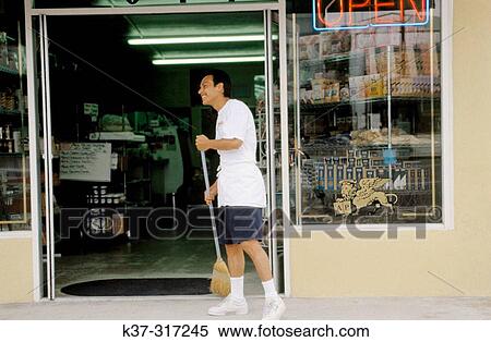 Stock Photography - Man sweeping sidewalk outside Italian pasta store in San Diego. USA. Fotosearch