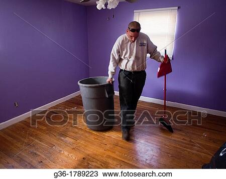Stock Image - Man sweeps floor in empty-room inside of a foreclosed home in Warwick, Rhode Island. Fotosearch
