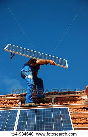 Stock Image - Man take a module of a Solar Powerstation at Instalation. Fotosearch