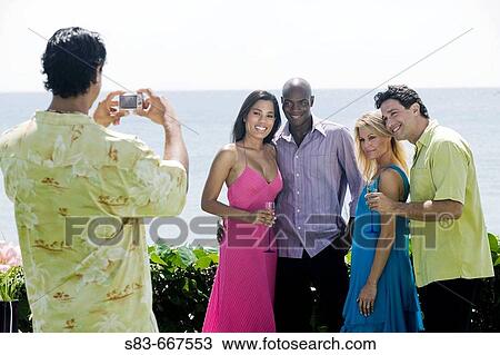 Stock Image - Man taking a group photo of people at the beach. Fotosearch