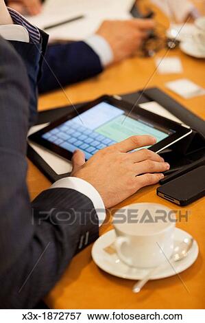Man taking notes on a tablet during a business meeting View Large Photo Image Stock Photo - Man taking notes on a tablet during a business meeting. Fotosearch