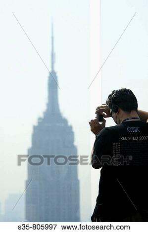Man taking photo of Empire State Building from the Top of the Rock observation deck of Rockefeller Center, New York City. USA View Large Photo Image Stock Photo - Man taking photo of Empire State Building from the Top of the Rock observation deck of Rockefeller Center, New York City. USA. Fotosearch