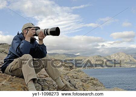 Man taking photograph of a landscape with telephoto, Hermanus, South Western Cape, South Africa View Large Photo Image Stock Image - Man taking photograph of a landscape with telephoto, Hermanus, South Western Cape, South Africa. Fotosearch