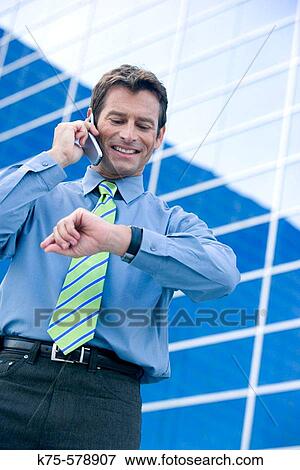 Man talking on cell phone and looking at his watch View Large Photo Image Stock Photo - Man talking on cell phone and looking at his watch. Fotosearch
