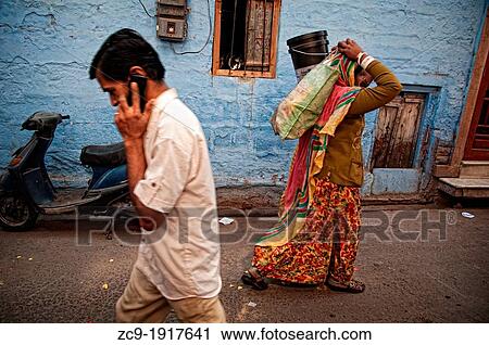 Man talking on mobile phone and woman carrying bags on her head in a typical blue street in old town Jodhpur, Rajasthan, India View Large Photo Image Stock Image - Man talking on mobile phone and woman carrying bags on her head in a typical blue street in old town Jodhpur, Rajasthan, India. Fotosearch