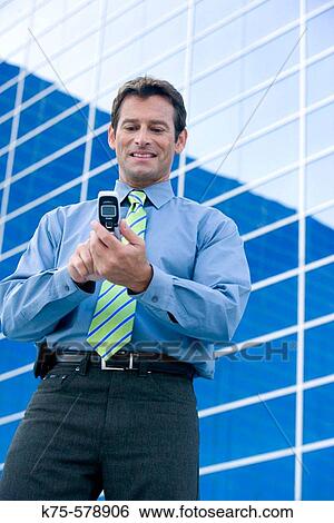 Man text messaging on cell phone outside office building View Large Photo Image Stock Photograph - Man text messaging on cell phone outside office building. Fotosearch
