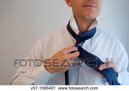 Stock Image - Man tying his necktie. Close view.. Fotosearch