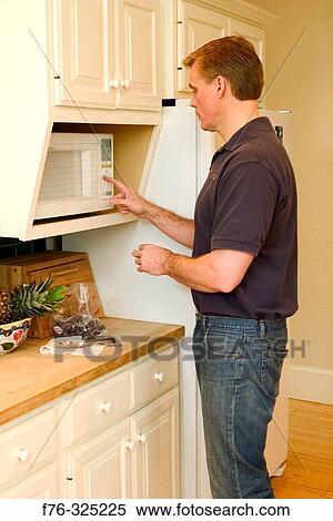 Man using microwave oven in kitchen View Large Photo Image Stock Photography - Man using microwave oven in kitchen. Fotosearch