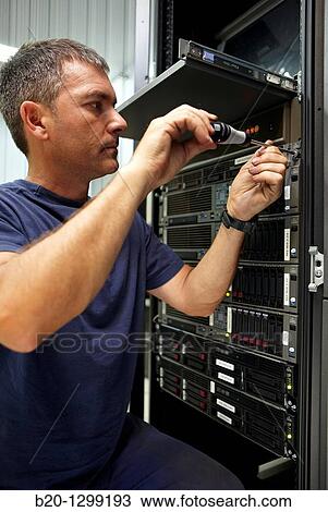 Stock Image - Man using screwdriver, compute cluster maintenance. Fotosearch