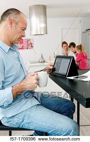 Stock Photograph - Man using tablet computer at home. Fotosearch