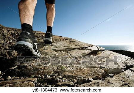 Stock Image - Man walking along a coastal path. Fotosearch
