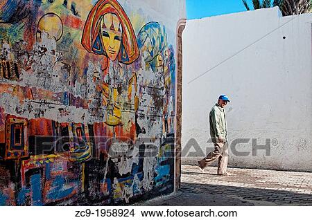 Man walking by the beautifully painted streets of Azemmour medina, Morocco. View Large Photo Image Picture - Man walking by the beautifully painted streets of Azemmour medina, Morocco.. Fotosearch