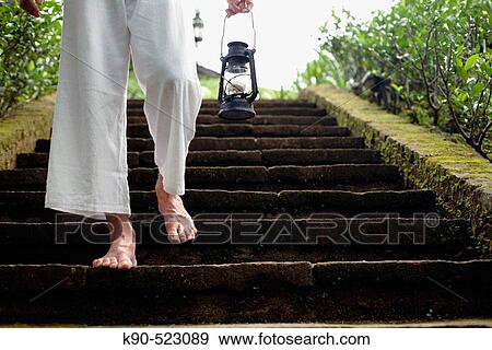 Man walking down the earthern stairs carrying an oil lamp at Losari Coffee Plantation in West Java, Indonesia, South East Asia View Large Photo Image Stock Photo - Man walking down the earthern stairs carrying an oil lamp at Losari Coffee Plantation in West Java, Indonesia, South East Asia. Fotosearch