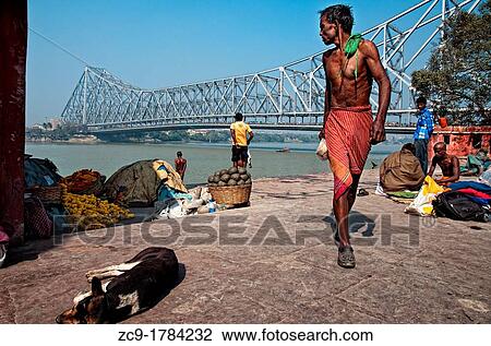 Man walking in Mullick ghat with Howrah bridge at the back Calcutta, India View Large Photo Image Stock Image - Man walking in Mullick ghat with Howrah bridge at the back Calcutta, India. Fotosearch