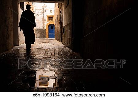 Man walking under a tunnel in Essaouira medina. Morocco. View Large Photo Image Picture - Man walking under a tunnel in Essaouira medina. Morocco.. Fotosearch