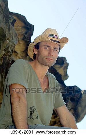 Man wearing a cowboy hat, sat on a rock. View Large Photo Image Stock Image - Man wearing a cowboy hat, sat on a rock.. Fotosearch