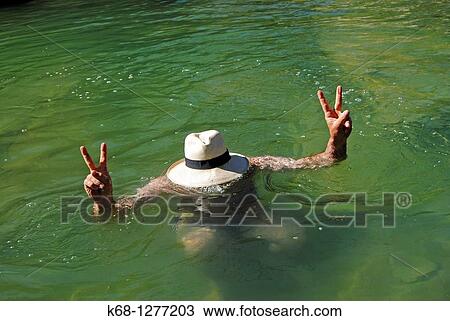 Stock Image - Man wearing a panama hat in the water of a creek. Fotosearch
