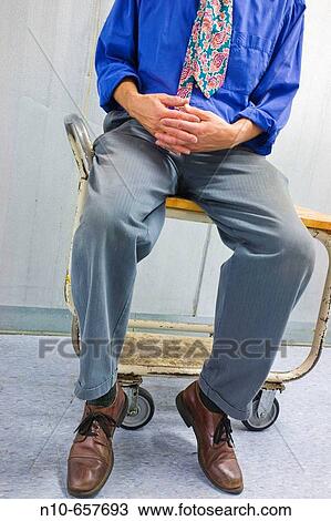 Man, wearing an uneven tie, sitting on a rolling cart. View Large Photo Image Stock Image - Man, wearing an uneven tie, sitting on a rolling cart.. Fotosearch