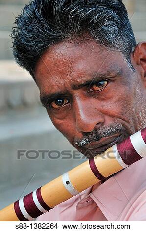Picture - Man who sells flute playing at the ghat by the Ganges river. Fotosearch