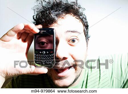 Man with a mobile phone with a photography of his eye View Large Photo Image Picture - Man with a mobile phone with a photography of his eye. Fotosearch