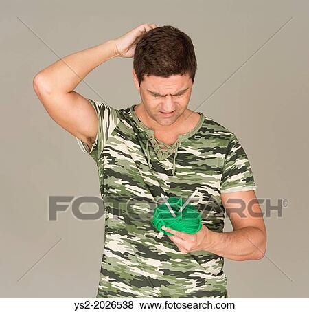 Man with camouflage t-shirt looking puzzled at a ball of yarn and knitting needles. View Large Photo Image Stock Photo - Man with camouflage t-shirt looking puzzled at a ball of yarn and knitting needles.. Fotosearch